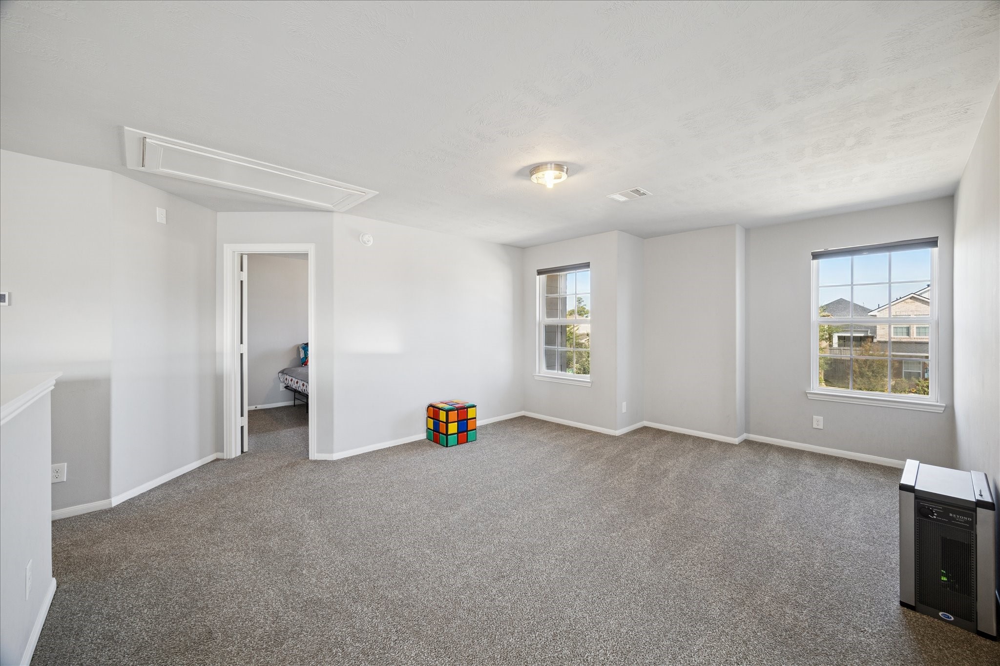 7610 Retama Terrace Lane Humble, TX 77338 - Photo 9 of 14 This spacious, carpeted room features neutral walls and ample natural light from two windows. It leads to another room and has a small colorful cube as decor, offering versatility for use as a living area or playroom.