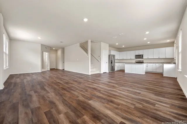 a view of a kitchen with kitchen island a sink wooden floor and a large window