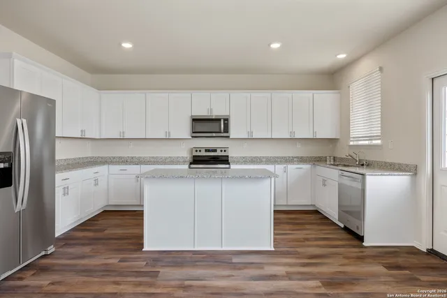 a kitchen with granite countertop white cabinets and stainless steel appliances