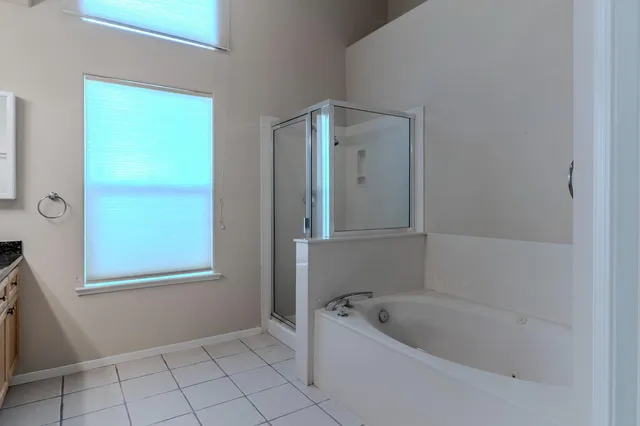 a bathroom with a bathtub a window and a shower