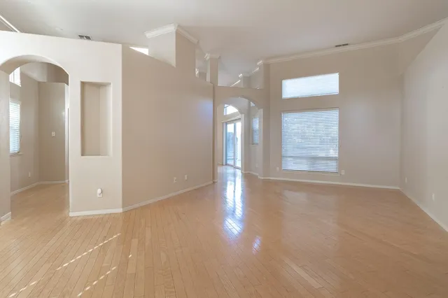 a view of an empty room with window and wooden floor