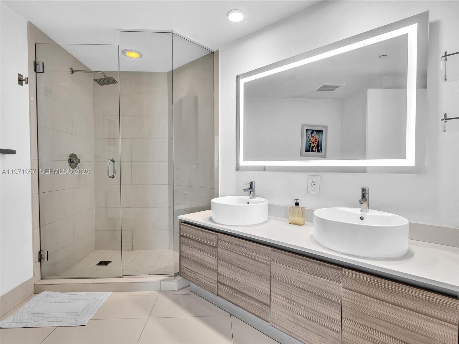 121 Northeast 34th Street, Unit 2016 Miami, FL 33137 - Photo 45 of 55 a bathroom with a shower sink vanity and mirror