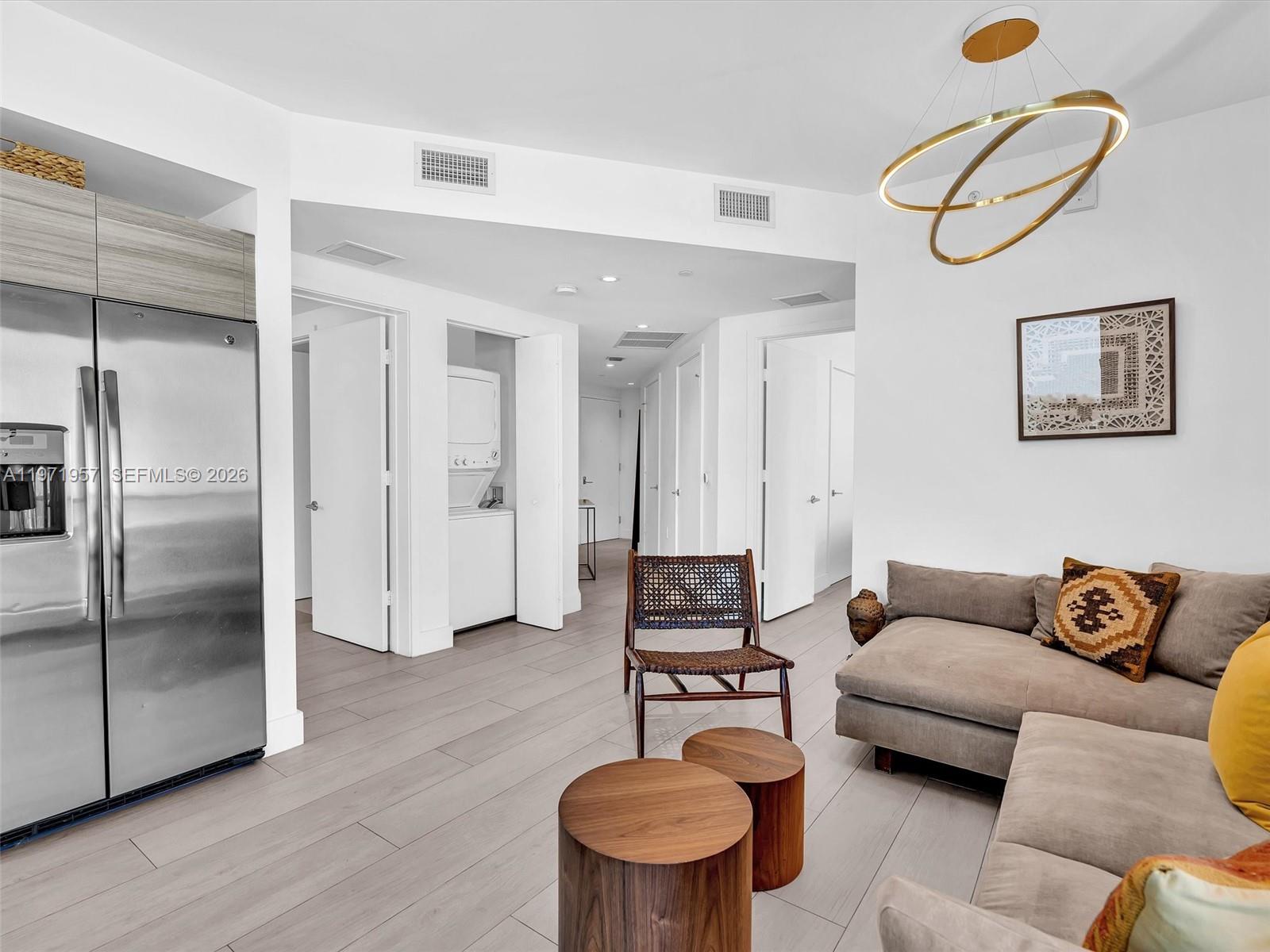 121 Northeast 34th Street, Unit 2016 Miami, FL 33137 - Photo 49 of 55 a living room with furniture a refrigerator and a table