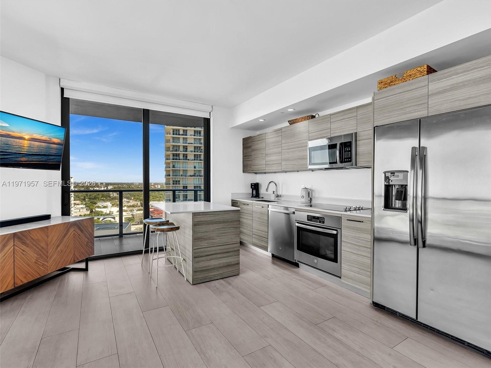 121 Northeast 34th Street, Unit 2016 Miami, FL 33137 - Photo 8 of 55 a kitchen with granite countertop a refrigerator and wooden floor
