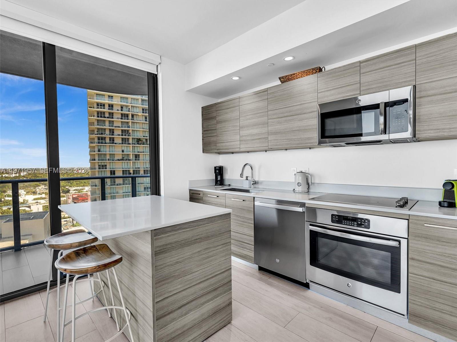 121 Northeast 34th Street, Unit 2016 Miami, FL 33137 - Photo 9 of 55 a kitchen with stainless steel appliances kitchen island a table and chairs in it