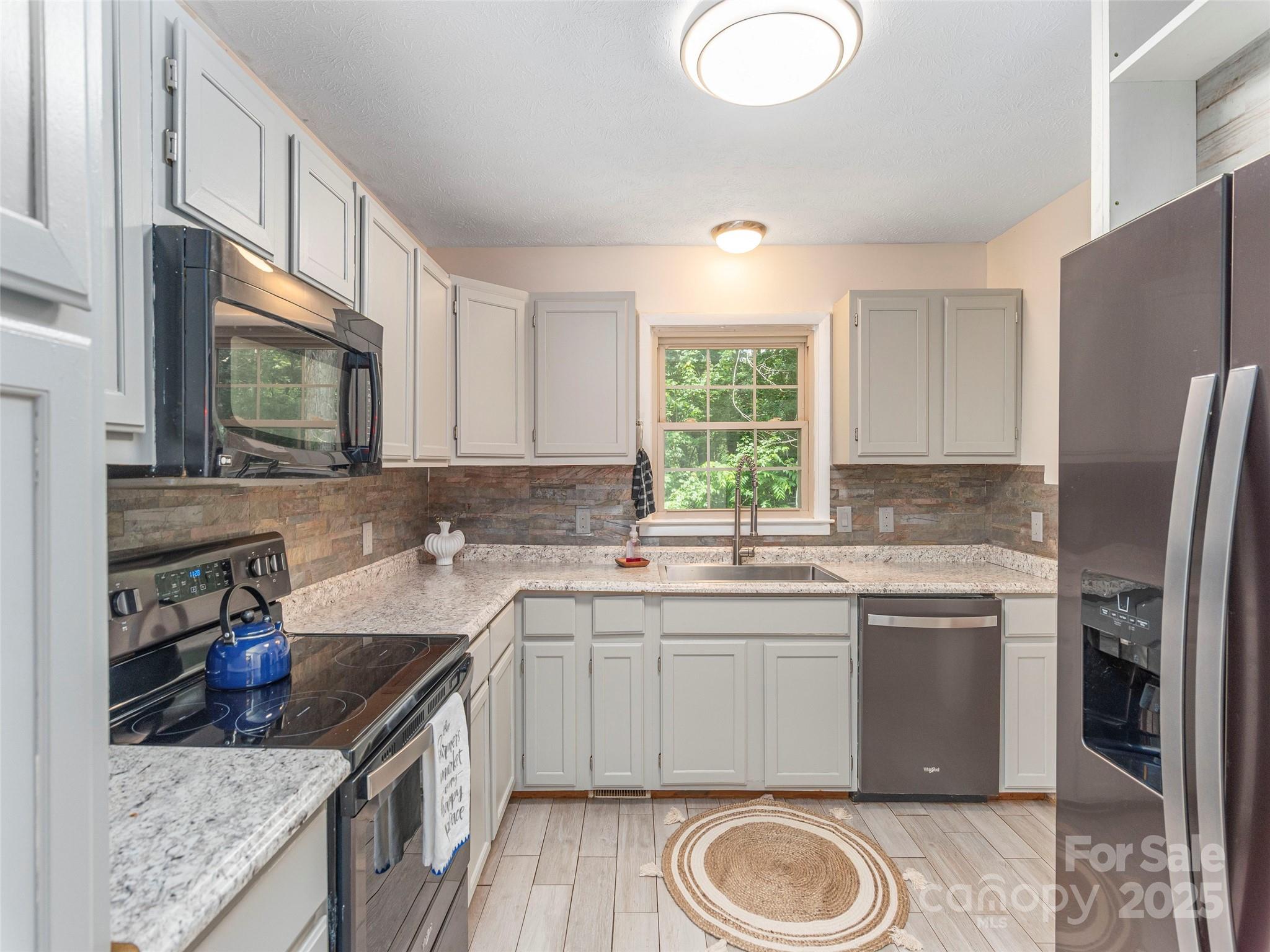 623 Nellie John Drive Clyde, NC 28721 - Photo 11 of 25 a kitchen with stainless steel appliances granite countertop a sink stove and refrigerator