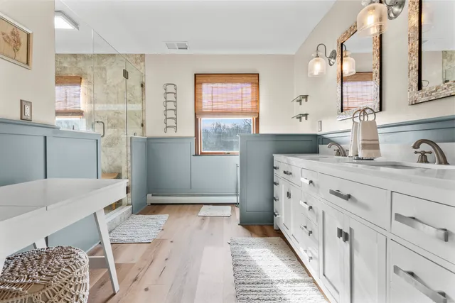 a bathroom with a sink a mirror a vanity and shower
