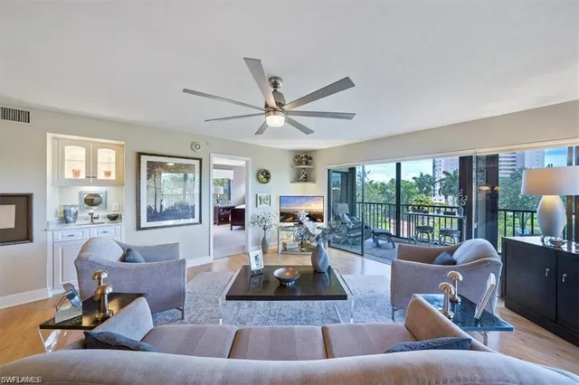 a living room with furniture large windows and wooden floor