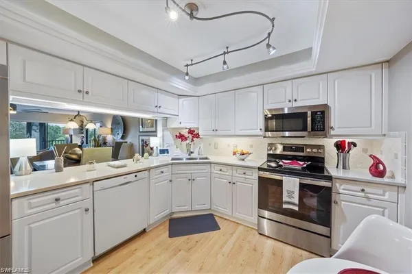 a kitchen with granite countertop a sink stainless steel appliances and white cabinets