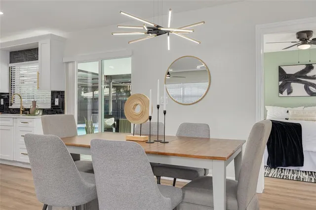 a living room with couches a dining table and large window with wooden floor