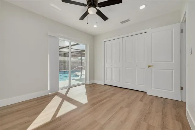 an empty room with wooden floor fan and windows