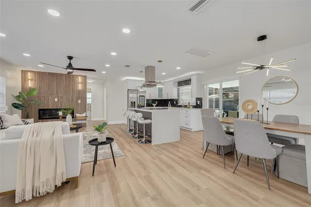 a living room with furniture kitchen view and a wooden floor