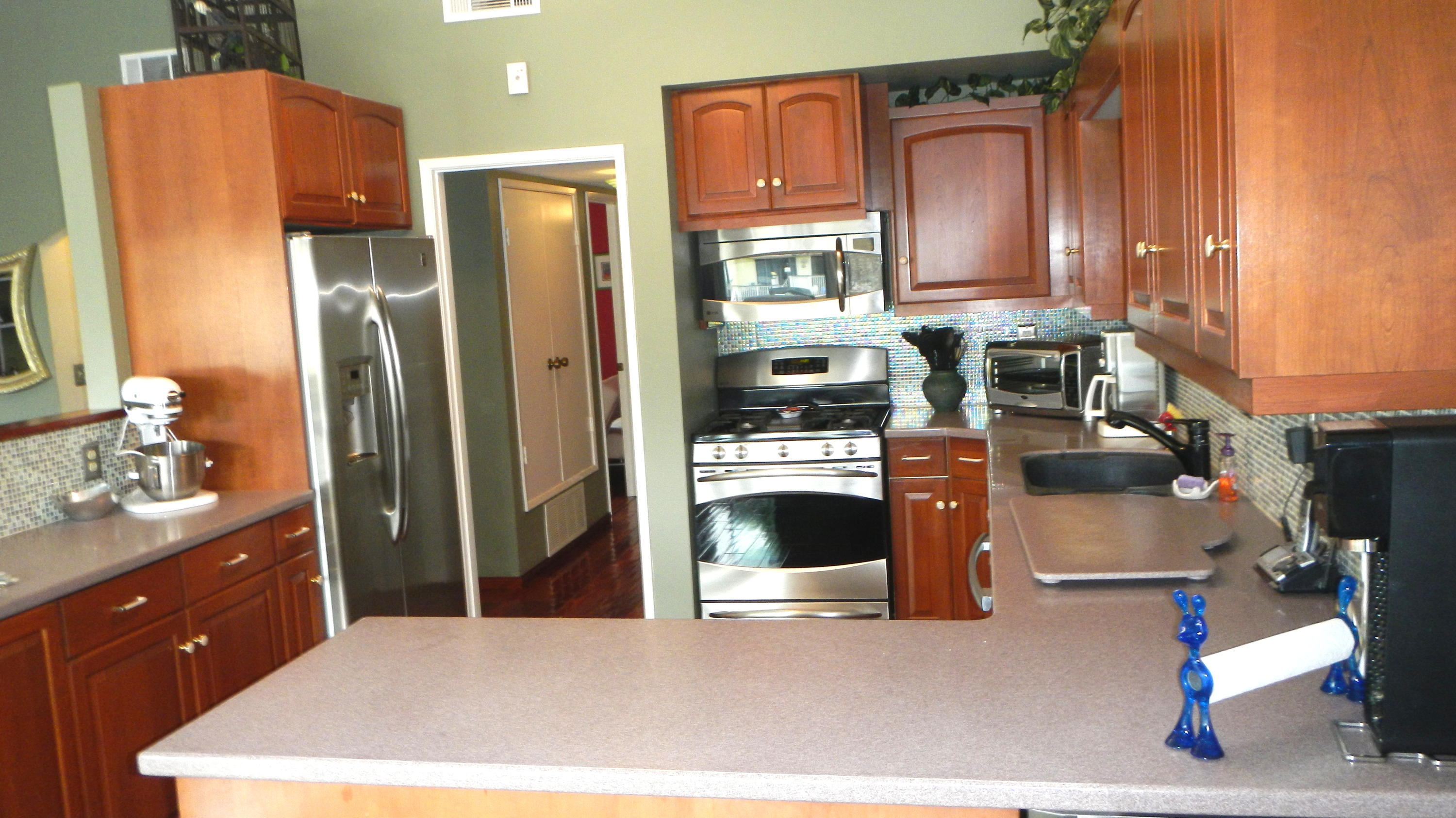 4640 Eastbourne Oxnard, CA 93035 - Photo 11 of 49 a kitchen with stainless steel appliances kitchen island granite countertop a refrigerator a stove and a sink with wooden floor