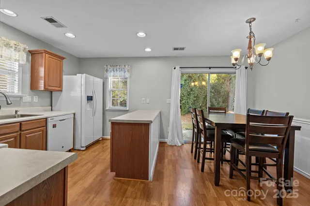 a kitchen with stainless steel appliances granite countertop wooden floor dining table and chairs