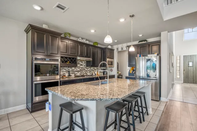 a kitchen with stainless steel appliances granite countertop a kitchen island wooden cabinets and granite counter tops