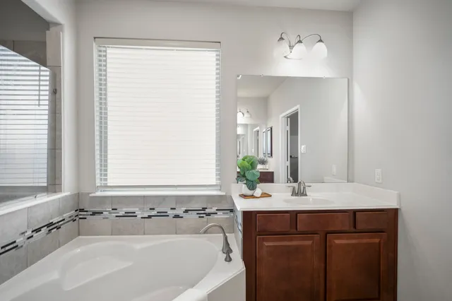 a spacious bathroom with a tub sink shower and mirror