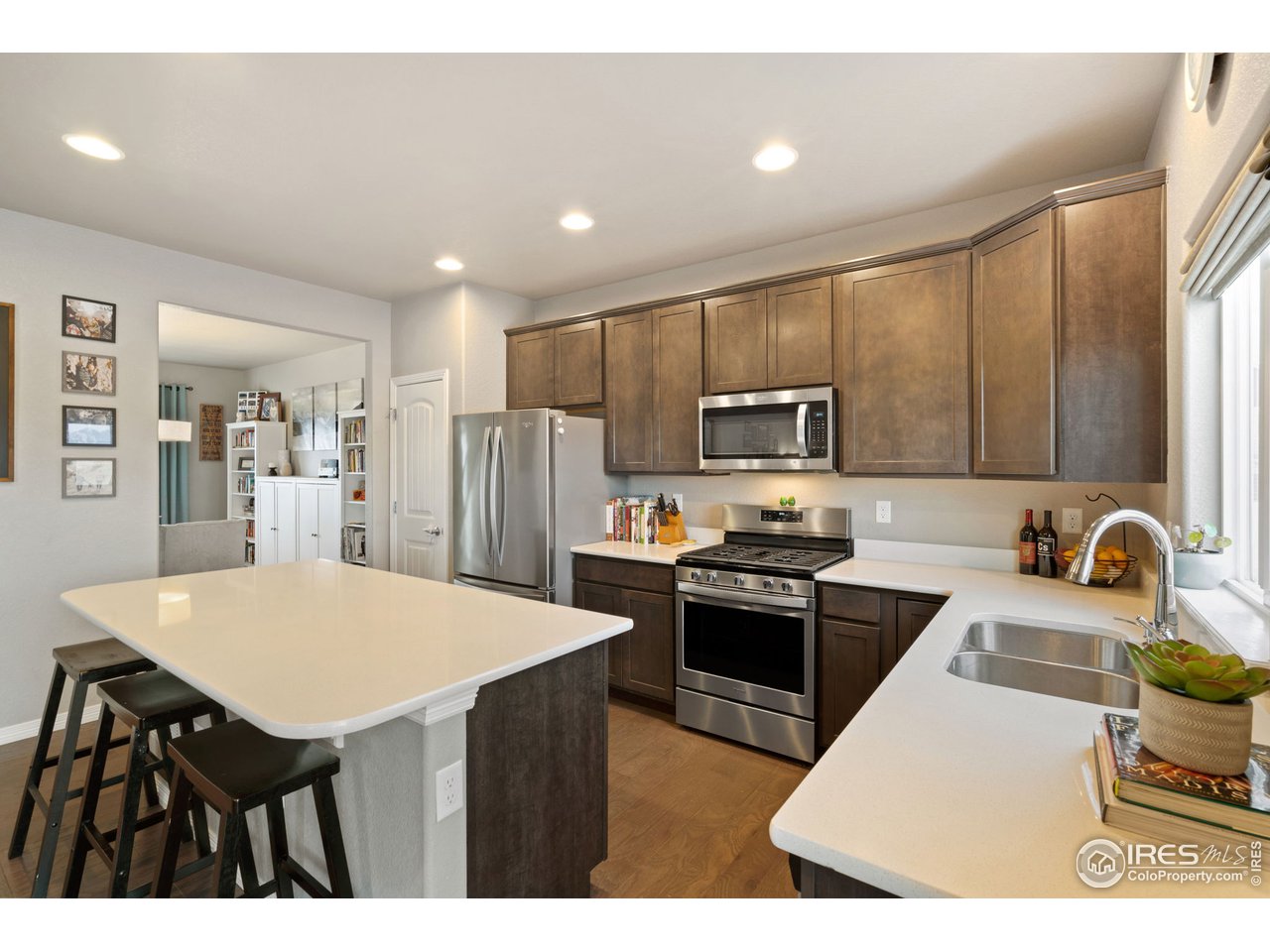 2499 Likens Drive Berthoud, CO 80513 - Photo 8 of 33 a kitchen with stainless steel appliances a stove a sink a microwave a refrigerator and white cabinets with wooden floor