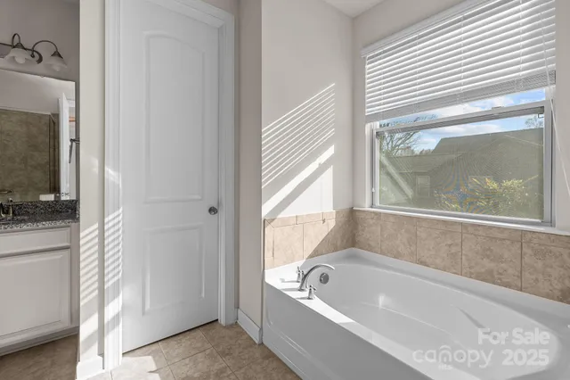 a bathroom with a tub a mirror and a window