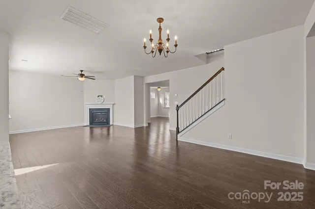 a view of an empty room with wooden floor and staircase