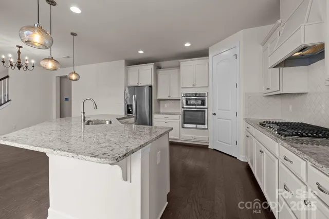 a kitchen with stainless steel appliances granite countertop a sink stove and refrigerator