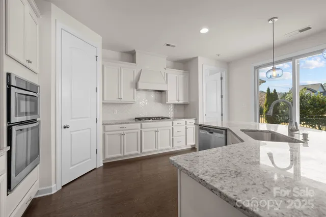 a kitchen with stainless steel appliances granite countertop a sink refrigerator and cabinets