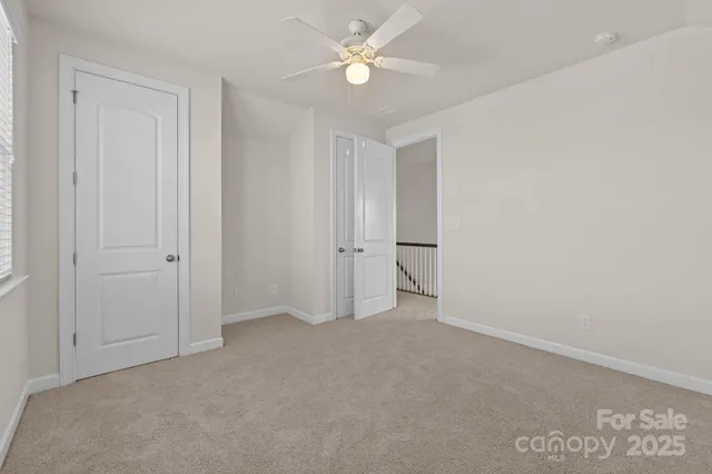 an empty room with closet and a ceiling fan