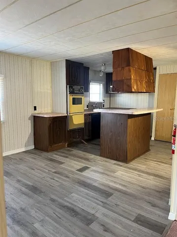 a view of kitchen with stainless steel appliances wooden floor and living room