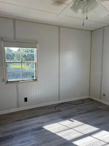a view of empty room with wooden floor and fan