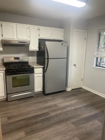 a kitchen with a stove a refrigerator and white cabinets