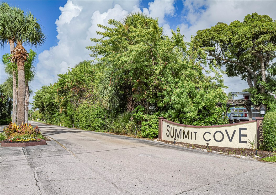 a view of sign board with yard and trees