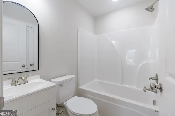 a bathroom with a bathtub shower sink vanity mirror and toilet