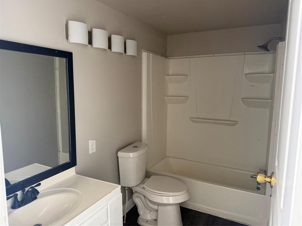 117 Aztec Way West Tawakoni, TX 75474 - Photo 10 of 12 Bathroom featuring a white vanity with an integrated sink, a rectangular mirror with a dark frame, and a white tub/shower combination with built-in shelving