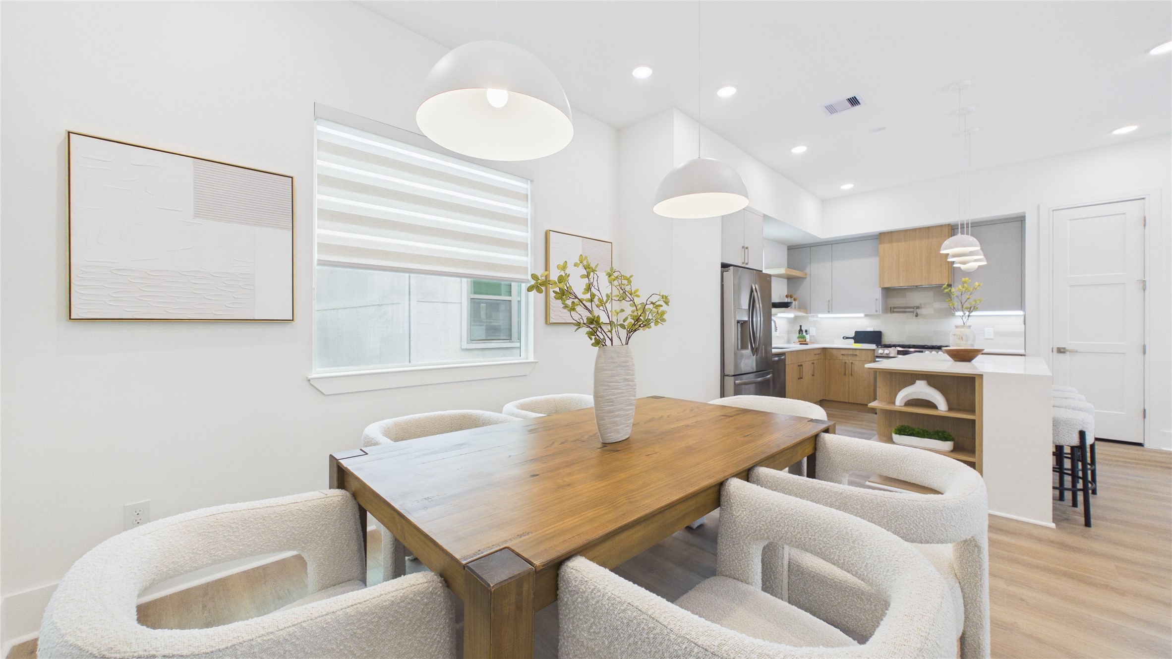 602 Skyland Terrace Way Houston, TX 77009 - Photo 17 of 40 This modern, open-concept kitchen and dining area features a sleek design with white walls, wooden floors, and contemporary pendant lighting. The kitchen includes stainless steel appliances and a cozy island with seating. The dining area boasts a stylish wooden table and comfortable chairs, creating a welcoming space for meals and gatherings.