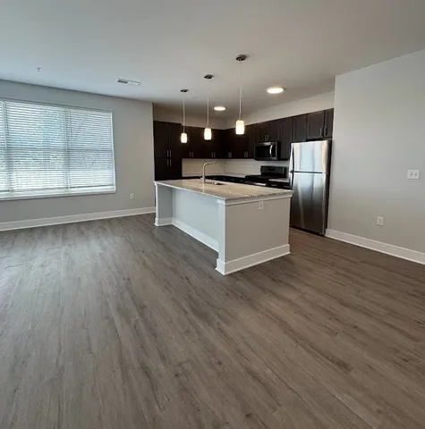 a view of kitchen with kitchen island granite countertop a stove top oven and a sink with granite countertops