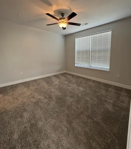 an empty room with closet and a ceiling fan