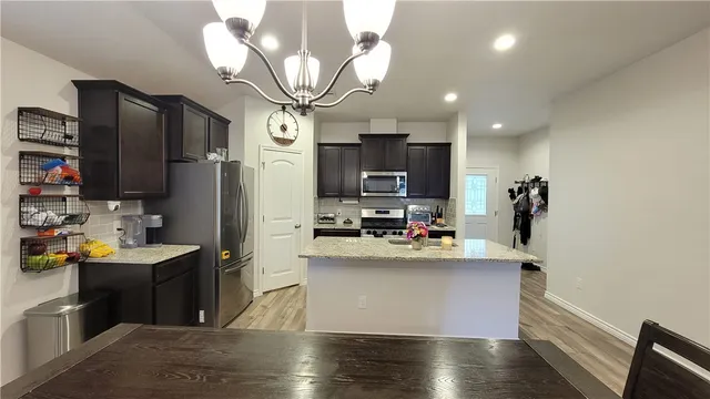 a view of a kitchen with kitchen island a sink appliances and cabinets