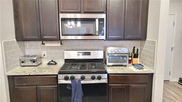 a kitchen with stainless steel appliances granite countertop a stove and a microwave