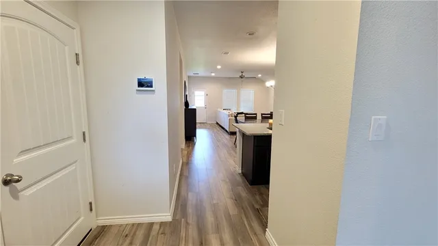 a view of a hallway with wooden floor windows and a kitchen