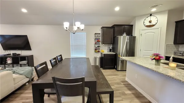 a kitchen with stainless steel appliances a dining table chairs and a refrigerator