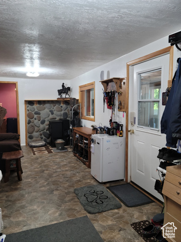 97 East Main Street Stockton, UT 84071 - Photo 44 of 58 Stone finish flooring, mini fridge, a textured ceiling, and a pellet stove