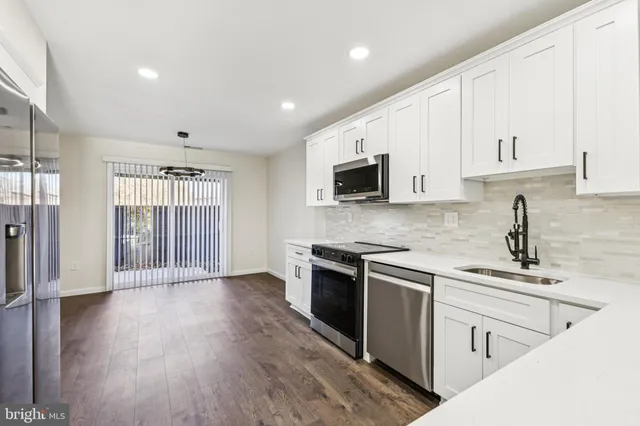 a kitchen with stainless steel appliances granite countertop a stove a sink dishwasher and a refrigerator with wooden floor