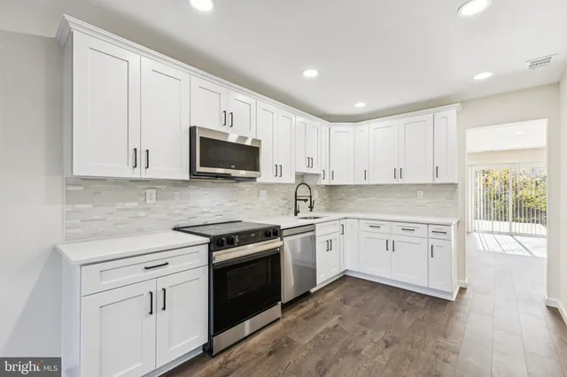 a kitchen with granite countertop white cabinets and stainless steel appliances