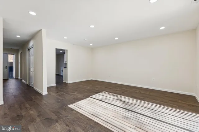 an empty room with wooden floor and natural light