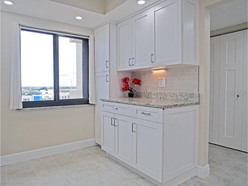 15000 Gulf Boulevard, Unit 1108 Madeira Beach, FL 33708 - Photo 6 of 20 a kitchen with granite countertop white cabinets and window