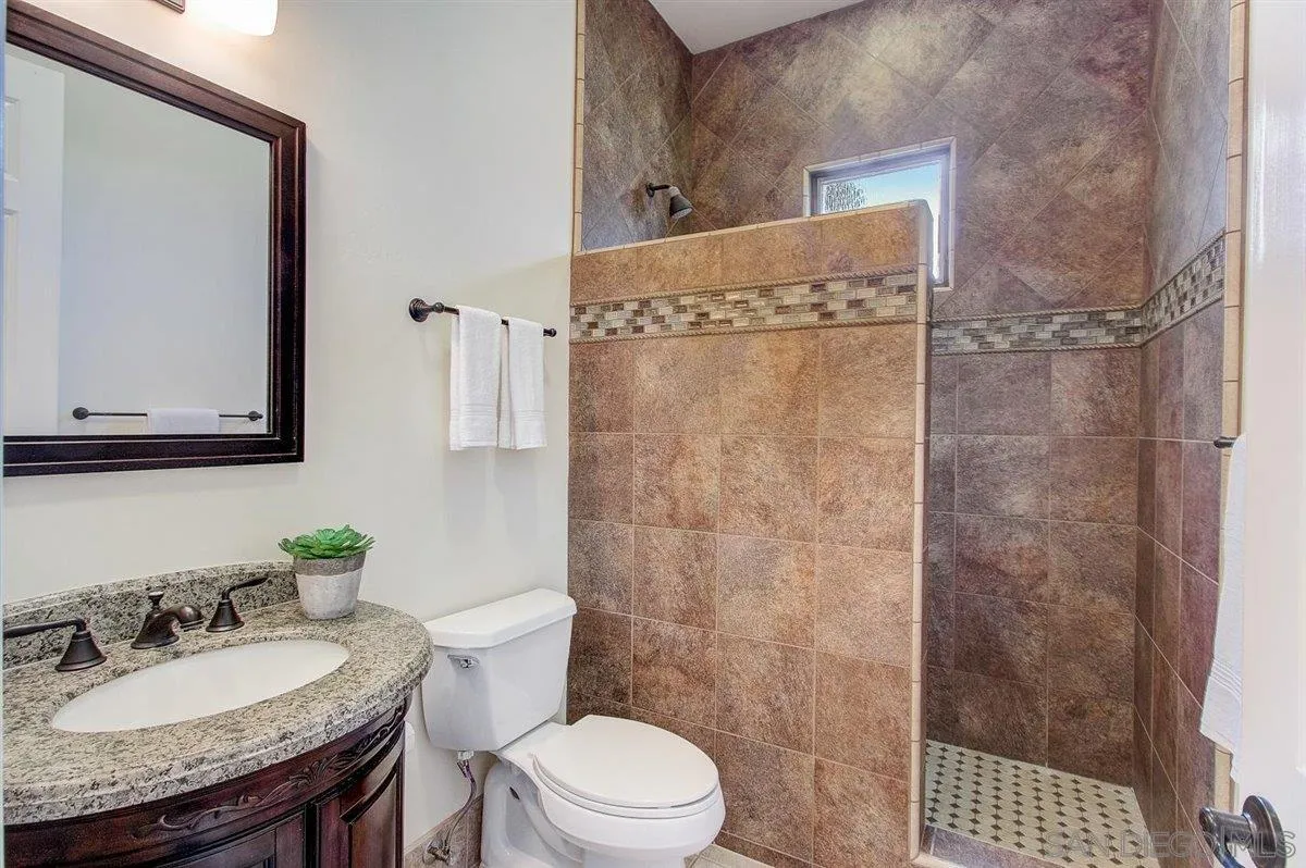 4349 Fallsbrae Road Fallbrook, CA 92028 - Photo 31 of 68 a bathroom with a granite countertop sink a mirror and a toilet