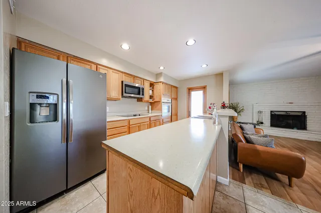 a living room with stainless steel appliances furniture a fireplace and a kitchen view