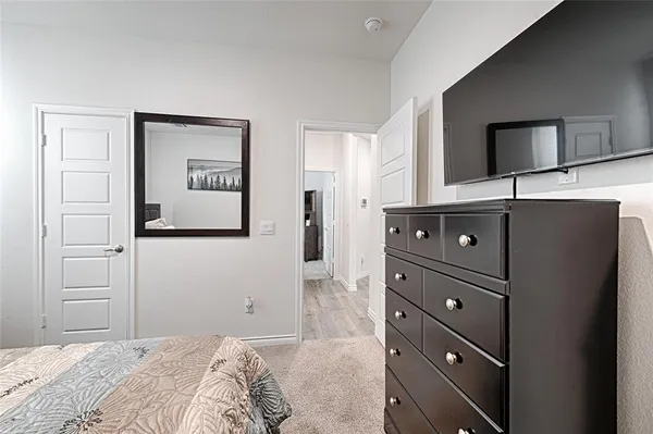 a bedroom with a bed and a flat tv screen on dresser
