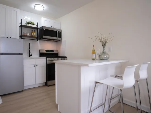 a kitchen with stainless steel appliances a sink a stove a microwave a refrigerator a cabinets and wooden floor