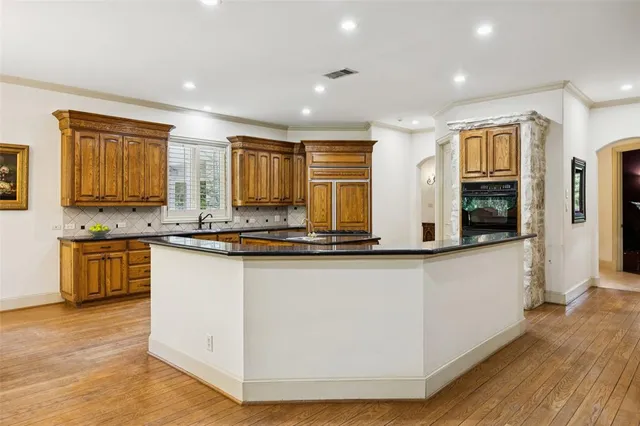 a large kitchen with stainless steel appliances granite countertop a large counter top a stove and a sink