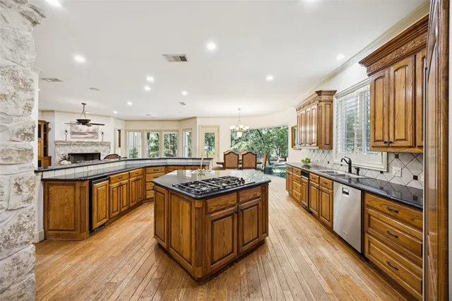 a kitchen with stainless steel appliances granite countertop a stove a sink dishwasher a refrigerator and white cabinets with wooden floor